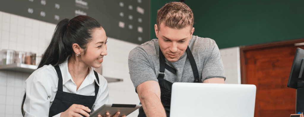 Two hospitality business owners viewing a laptop screen